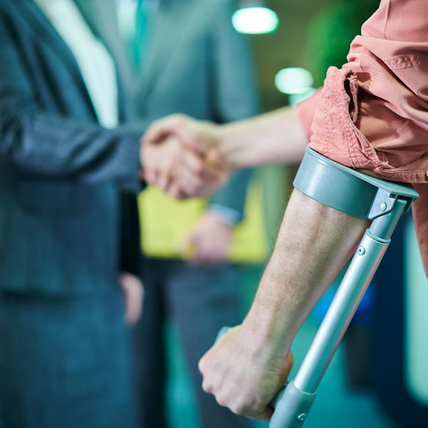man with crutch shaking hands with lawyer